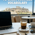A laptop and a freddo espresso on a desk in Athens, illustrating a guide to Greek business vocabulary for expats and digital nomads.